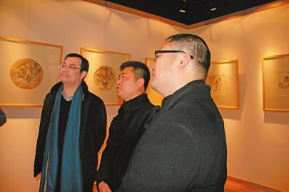瑞驰·齐鲁茶城总经理张连望（左一）与樊磊、刘扬两位画家在欣赏讨论他们的画作